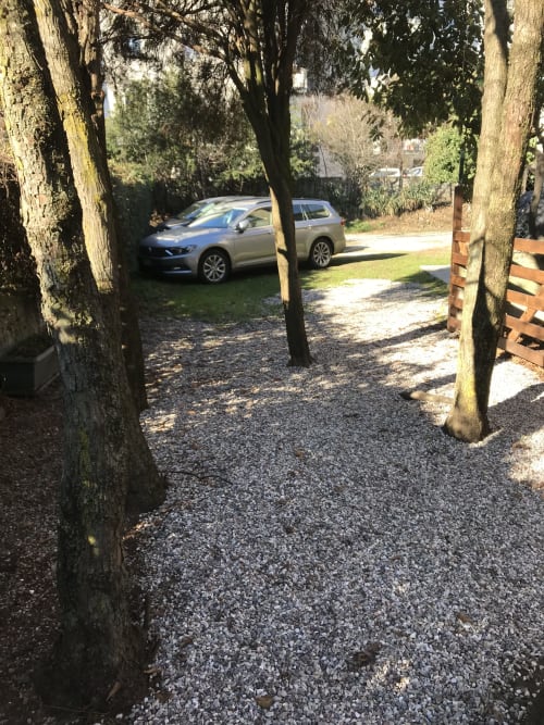 Tree-lined gravel driveway at Corte Roveggia hotel in Verona with parked cars and green gardens