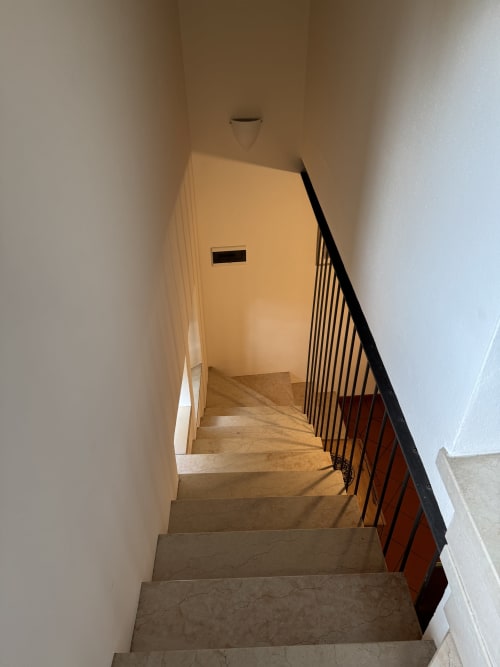 Staircase with metal railing at Corte Roveggia apartment in Verona, leading to upper level with modern lighting