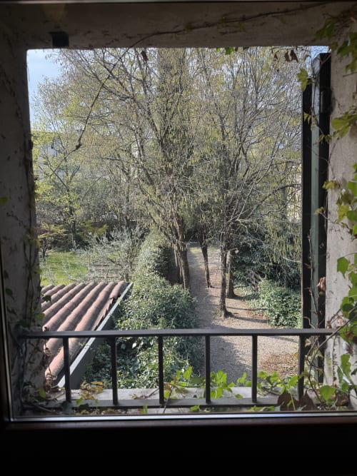 Garden view from Bilocale Dalì apartment at Corte Roveggia hotel in Verona, showing trees and pathways through lush grounds