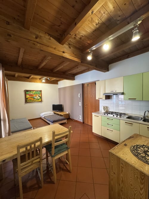 Bilocale Dalì apartment at Corte Roveggia in Verona with wooden beams, dining area, kitchen, and bedroom