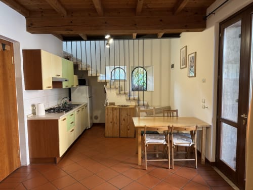 Bilocale Dalì apartment kitchen and dining area at Corte Roveggia in Verona with wooden table and garden view