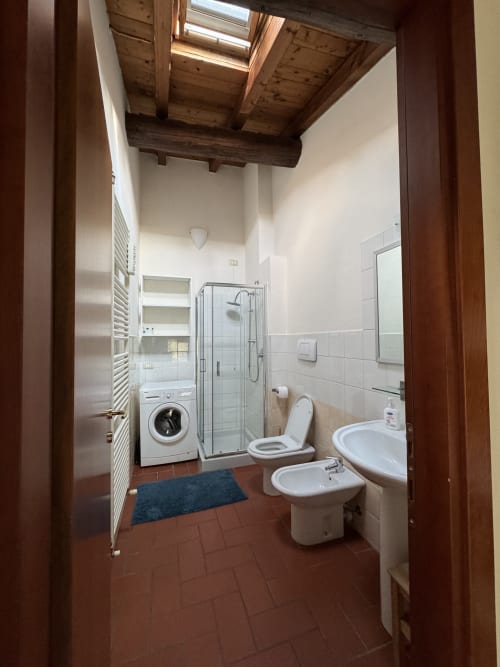 Modern bathroom at Corte Roveggia, Verona with shower, toilet, bidet, sink, and washing machine