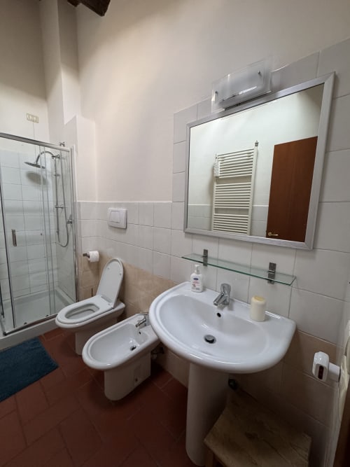 Modern bathroom with white sink, toilet, and shower in Bilocale Dalì apartment at Corte Roveggia hotel, Verona