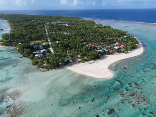 Aerial view of Tikehau Herearii beachfront bungalow resort in French Polynesia with turquoise lagoon and palm trees