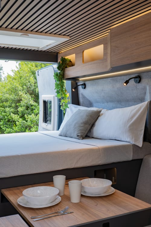 Dormitorio moderno en La Nómada Por Cien Vinos con techo forrado en madera, mesa de comedor y vistas panorámicas al jardín en España
