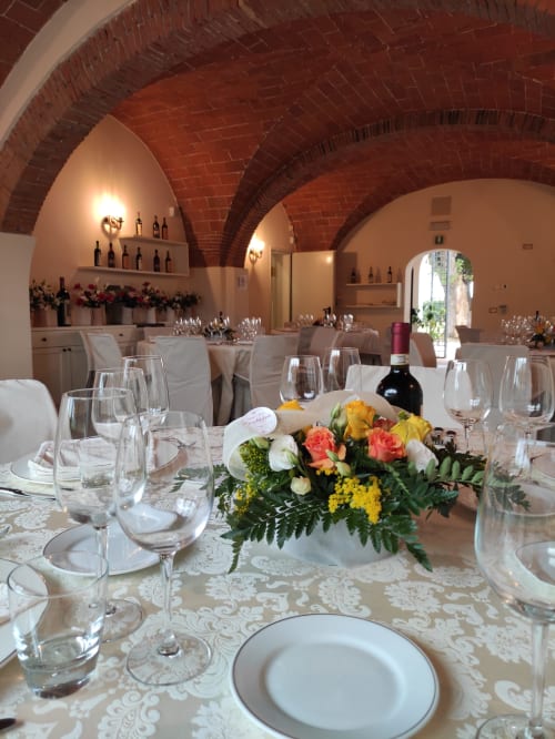 Elegant banquet hall with red brick arches, set dining table with floral centerpiece at Il Casale di David B&B in Pontedera
