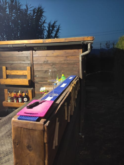 Outdoor bar setup at Il Casale di David B&B in Pontedera with wooden counter, pink cornhole boards, and bottles on display