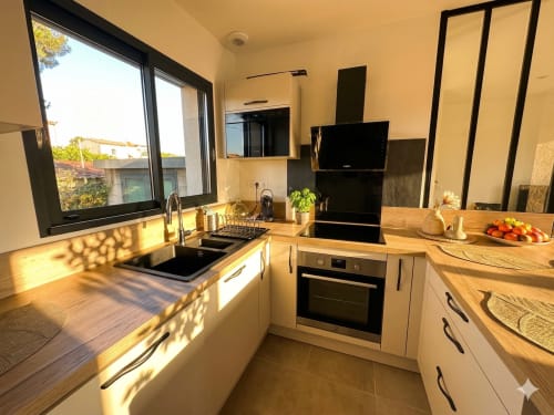 Cuisine moderne de La villa Métisse à la Conciergerie IB, Canet-en-Roussillon avec comptoirs en bois, électroménagers noirs et lumineuse