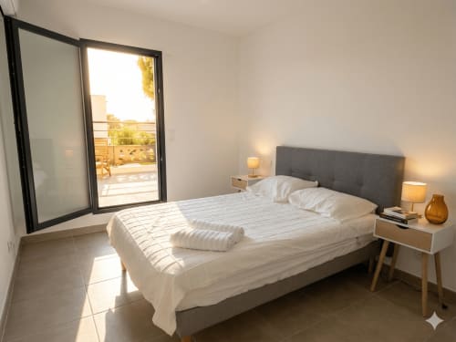 Chambre moderne avec tête de lit grise, literie blanche et accès à la terrasse jardin de La villa Métisse, Canet-en-Roussillon