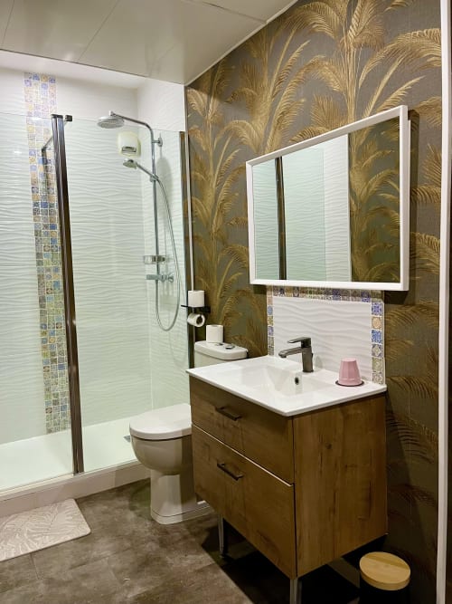 Salle de bain moderne du Manoir des Haies avec meuble-lavabo en bois, miroir éclairant et douche à l'italienne aux mosaïques