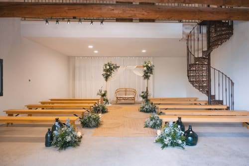 Élégante cérémonie de mariage au Mas de la Vernède à Aramon avec bancs en bois, compositions florales et chaises en rotin
