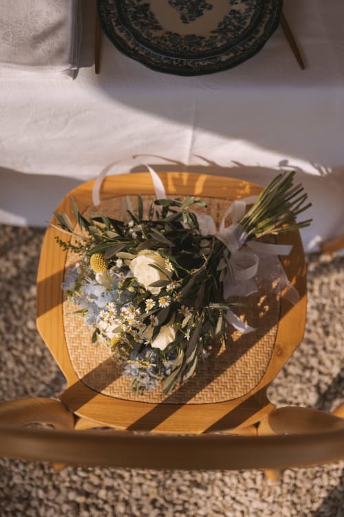Chaise rustique en bois avec bouquet de mariée de fleurs blanches et verdure au Mas de la Vernède, Aramon