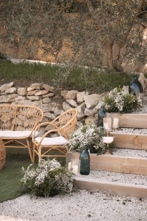 Coin de détente rustique au Mas de la Vernède à Aramon avec fauteuils en osier, fleurs blanches et éléments en pierre