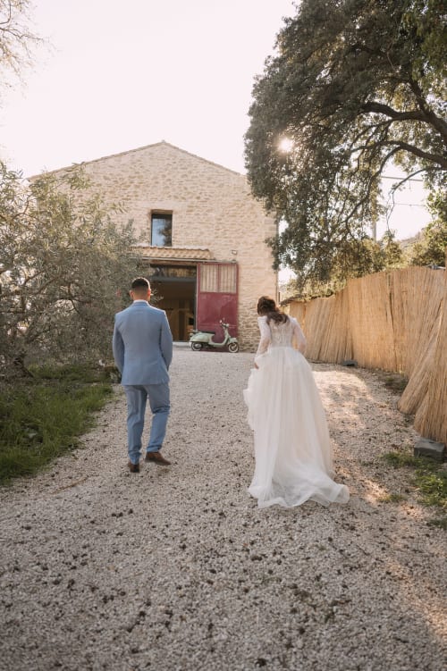 Les mariés se dirigent vers la grange en pierre du domaine Le Mas de la Vernède à Aramon, France