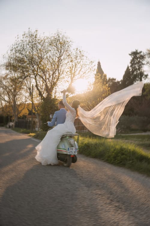 Mariés sur un scooter vintage avec voile flottant près du Mas de la Vernède à Aramon, France