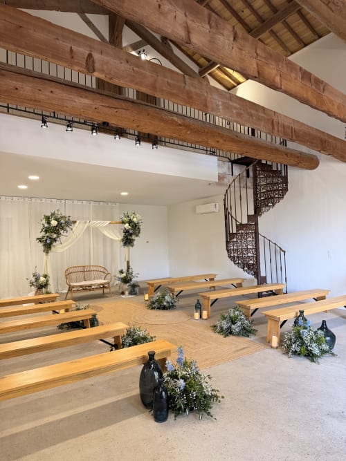 Espace de cérémonie rustique au Mas de la Vernède à Aramon avec poutres en bois, bancs et compositions florales
