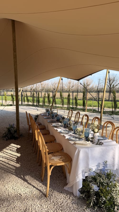 Élégante mise en place de repas en plein air sous voile d'ombrage beige au Mas de la Vernède, Aramon, avec longue table et chaises en bois