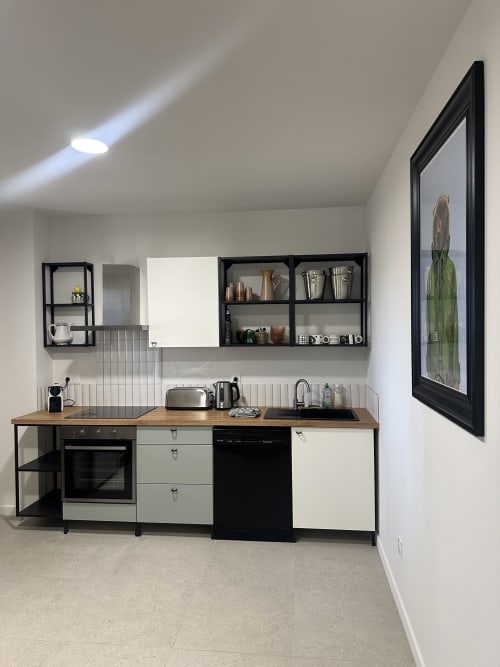Kitchenette moderne au Mas de la Vernède : mobilier noir et blanc, plan de travail bois, tableau de cactus, Aramon
