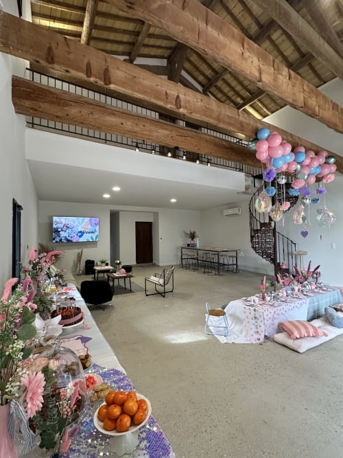 Salle d'événements Le Mas de la Vernède décorée de ballons roses et bleus, fleurs et tables de restauration à Aramon, France.