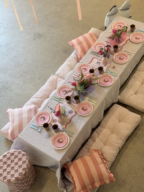 Mise en place de pique-nique au Mas de la Vernède avec table rose, assiettes décoratives, fleurs et coussins à Aramon