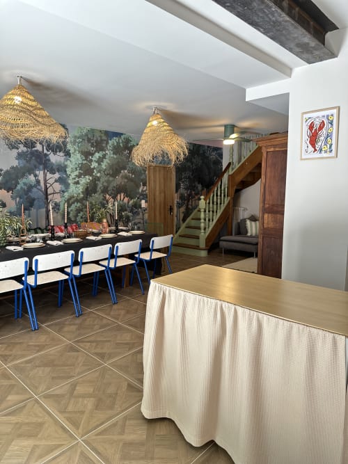 Modern dining room at Le Mas de la Vernède in Aramon with blue chairs, woven pendant lights, and forest mural