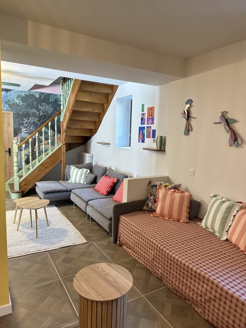 Spacious living area at Le Mas de la Vernède cottage with gray sofa, checkered daybed, wooden staircase, and modern decor in