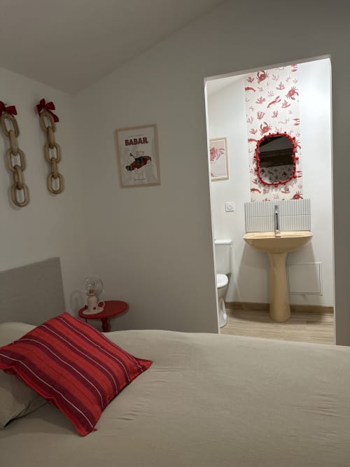 Bedroom with red striped pillow and ensuite bathroom with pedestal sink at Le Mas de la Vernède cottage, Aramon