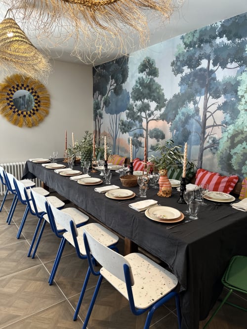 Elegant dining setup at Le Mas de la Vernède with forest mural, black table, and blue chairs in Aramon