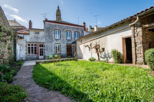 Cour charmante de la villa Bise de la Jouvence près du Puy du Fou, avec bâtiments en pierre, pelouse verdoyante et mobilier extérieur