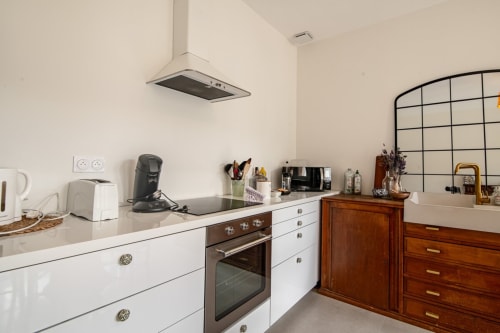 Cuisine moderne de la villa Bise de la Jouvence près du Puy du Fou avec armoires blanches, four inox, cafetière et