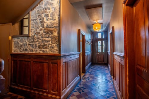 Élégant couloir de la villa Bise de la Jouvence à Saint Laurent sur Sèvre avec lambris bois, mur en pierre et carrelage à motifs