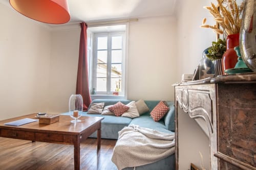 Salon chaleureux avec canapé turquoise, table en bois, cheminée et vue sur la ville au B&B Bise de la Jouvence près du Puy du Fou