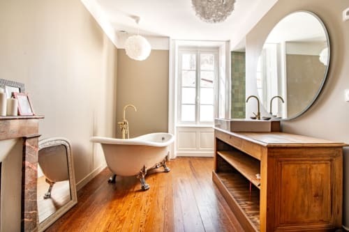 Salle de bain luxueuse à la villa Bise de la Jouvence avec baignoire îlot, meuble-lavabo en bois, miroir rond et parquets près du Puy