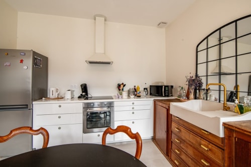 Cuisine moderne avec mobilier blanc, appareils en acier inoxydable et accents bois à la villa Bise de la Jouvence près du Puy du