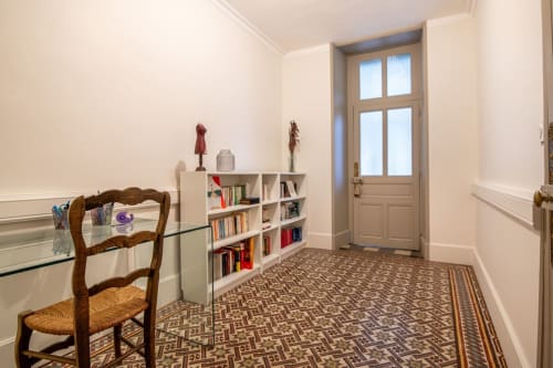 Espace de travail lumineux à la villa Bise de la Jouvence avec chaise en bois, étagères blanches, sol à motifs et portes vitrées