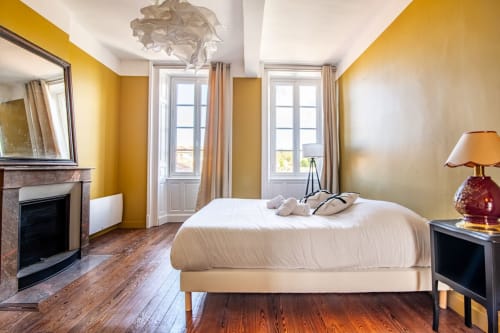 Chambre lumineuse jaune vif avec lit blanc, cheminée et vue sur la ville à la villa Bise de la Jouvence près du Puy du Fou, Saint Laurent