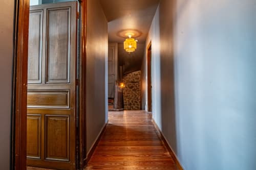 Couloir élégant de la villa Bise de la Jouvence à Saint Laurent sur Sèvre, avec porte en bois, éclairage chaleureux et plancher en bois dur