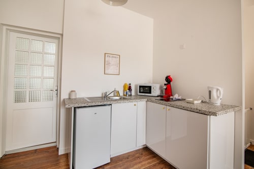Modern kitchenette with white cabinets and granite countertop at Bise de la Jouvence apartment near Puy du Fou