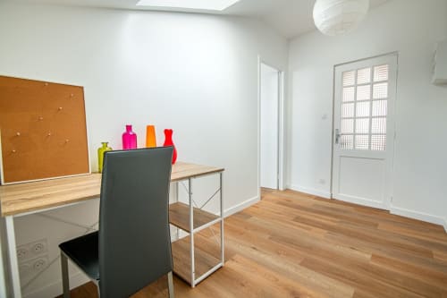 Bright modern apartment workspace with desk, chair, cork board, and colorful bottles near Puy du Fou, Saint Laurent sur Sèvre