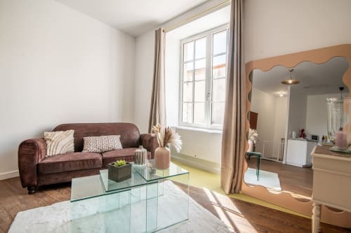 Bright modern apartment living room with burgundy sofa, glass table, and city views at Bise de la Jouvence near Puy du Fou,