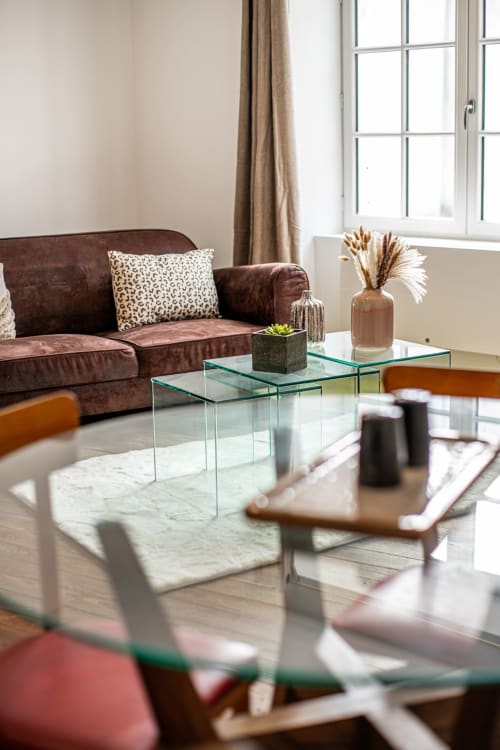 Modern living room at Bise de la Jouvence with burgundy sofa, glass tables, and bright windows in Saint Laurent sur Sèvre