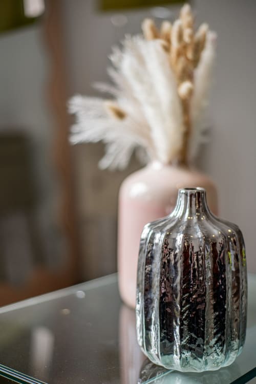 Clear glass textured bottle and pink vase with white flowers on table at Bise de la Jouvence apartment, Saint Laurent sur