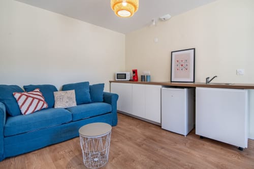 Studio moderne à Bise de la Jouvence avec canapé bleu, cuisine blanche et parquet, près du Puy du Fou.