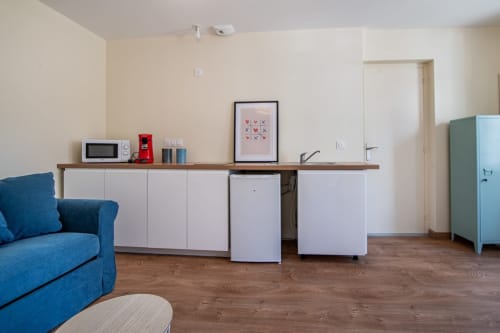 Studio moderne à Bise de la Jouvence avec fauteuil bleu, kitchenette et coin repas près du Puy du Fou