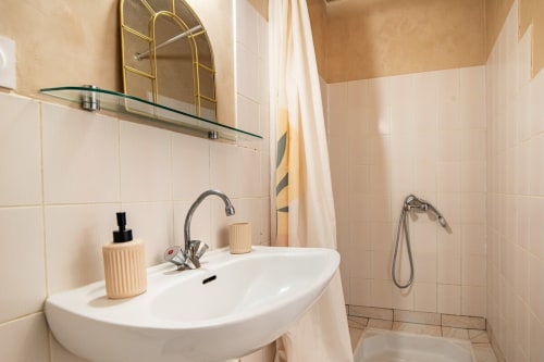Salle de bains moderne du studio Bise de la Jouvence près du Puy du Fou avec lavabo sur piédestal blanc, miroir doré et