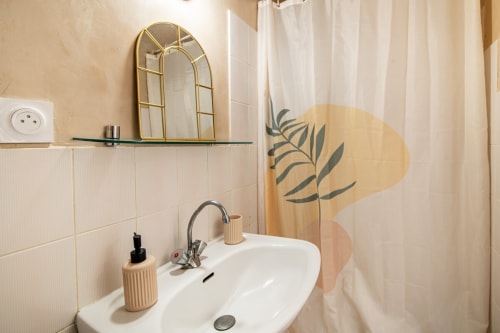 Lavabo de salle de bain moderne avec miroir doré cintre, carrelage blanc subway et art botanique au Studio 3 de Bise de la Jouvence