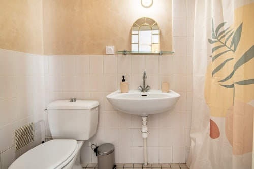 Salle de bain moderne du studio Bise de la Jouvence près du Puy du Fou, avec lavabo blanc, toilettes et décoration murale végétale