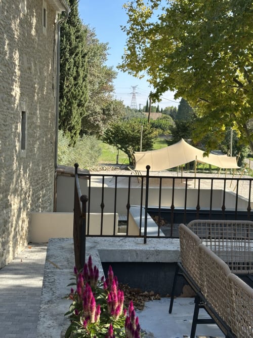 Terrace view at Le Mas de la Vernède cottage with magenta flowers, shaded seating, and countryside landscape in Aramon,