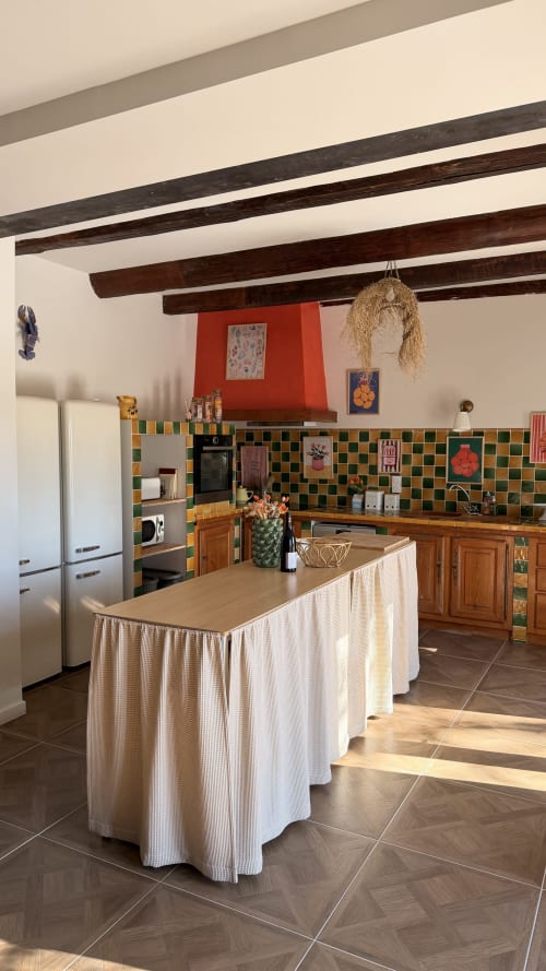 Rustic kitchen at Le Mas de la Vernède with exposed beams, checkered tiles, and central island in Aramon