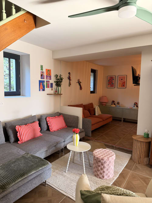 Modern living room at Le Mas de la Vernède with gray sofa, orange accents, and warm wood tones